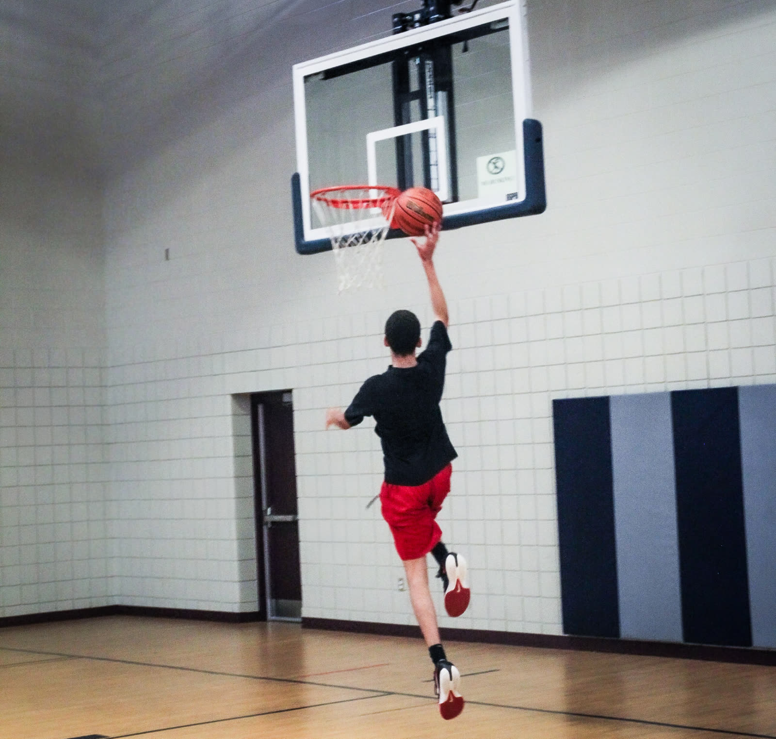 The Next Level athlete rising to finish at the rim in an empty gym